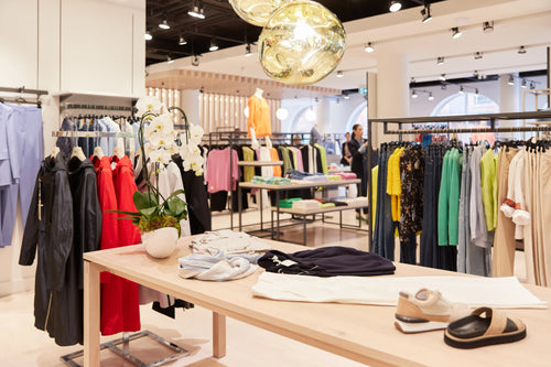 In-store view of Yorkville village location, display of various clothing and gold chandelier. 